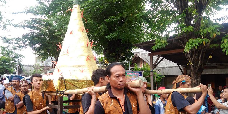 Gunungan besar berisi nasi kuning dalam Peringatan Haul KH. Syafii, diarak warga Desa Pongangan, Kecamatan Manyar, Gresik, Jawa Timur dengan menggenakan baju adat.
