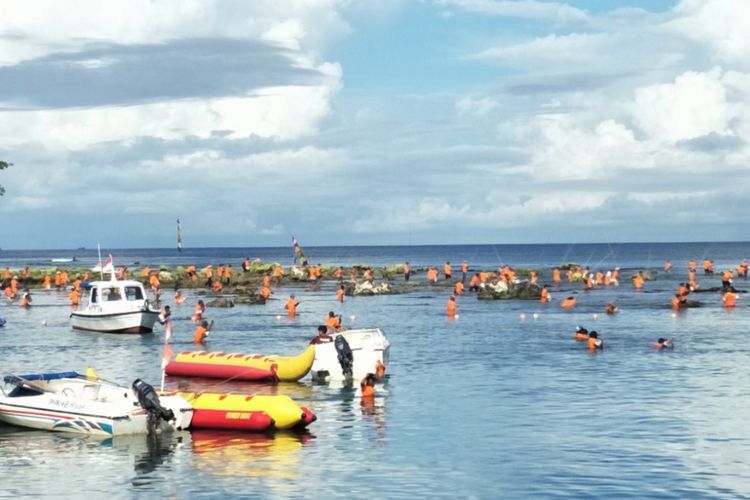 Ratusan warga mengenakan kaos seragam berwarna oranye, berjalan menuju laut, membawa bambu dengan panjang antara 5 hingga 6 meter dan mengikuti lomba memancing tradisional di Pantai Carita, Kabupaten Pandeglang, Banten, Selasa (12/2/2019).