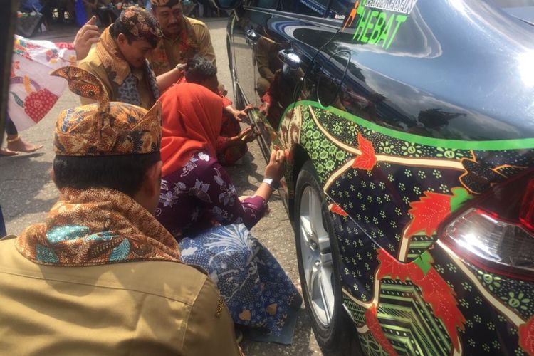 Bupati Pamekasan, Badrut Tamam melihat pengrajin batik mempraktekkan mbatik di mobil dinas yang sudah dipasangi stiker batik motif sekar jagad. 