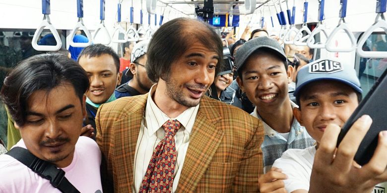 Artis peran Reza Rahadian yang berdandan ala Bossman di My Stupid Boss 2 berswafoto dengan penumpang MRT di MRT Jakarta rute Bundaran HI-Lebak Bulus, Jumat (29/3/2019).