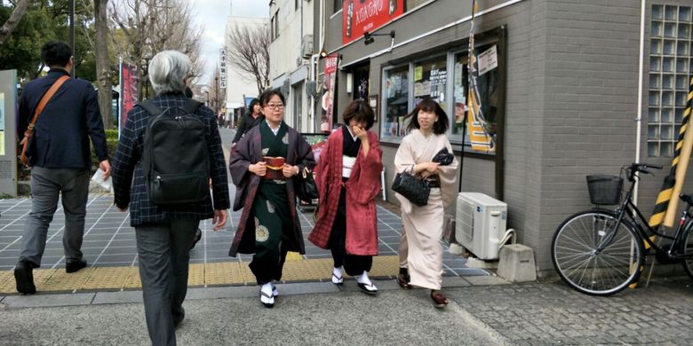 Wisatawan mengenakan kimono saat jalan-jalan di kawasan Miyuki-dori, Himeji, Jepang, Minggu (4/3/2018).