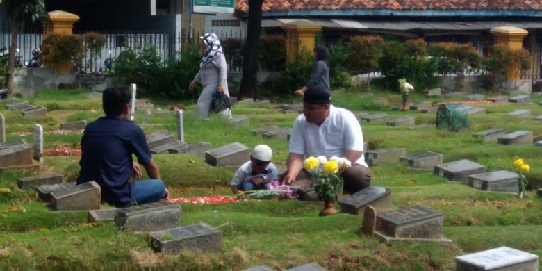 Ismet (kiri) bersama Amin dan anaknya (kanan) sedang melakukan ziarah kubur di Hari Pertama Lebaran di makam anggota keluarganya yang ada di TPU Jogol, Jumat (15/6/2018).