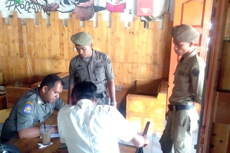 Satpol PP Lhokseumawe mendata seorang pegawai negeri yang duduk di warung kopi saat jam kerja di Kota Lhokseumawe, Aceh, Selasa (30/7/2019)