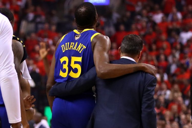 Power forward Golden State Warriors, Kevin Durant, dibantu berjalan setelah mengalami cedera pada gim kelima final NBA 2019 melawan Toronto Raptors, di Scotiabank Arena, Senin (10/6/2019). Usai laga, ia dipastikan mengalami cedera achilles.