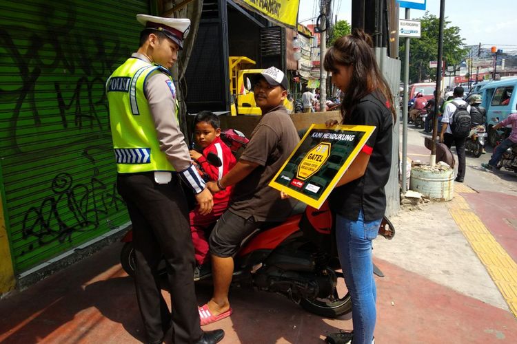 Petugas kepoliian dari NTMC Polri memberikan penyuluhan pada pengendara yang menggunakan trotoar tidak sesuai peruntukannya pada kampanye Gerakan Tertib Lalu lintas Kompas Otomotif dan Otomania