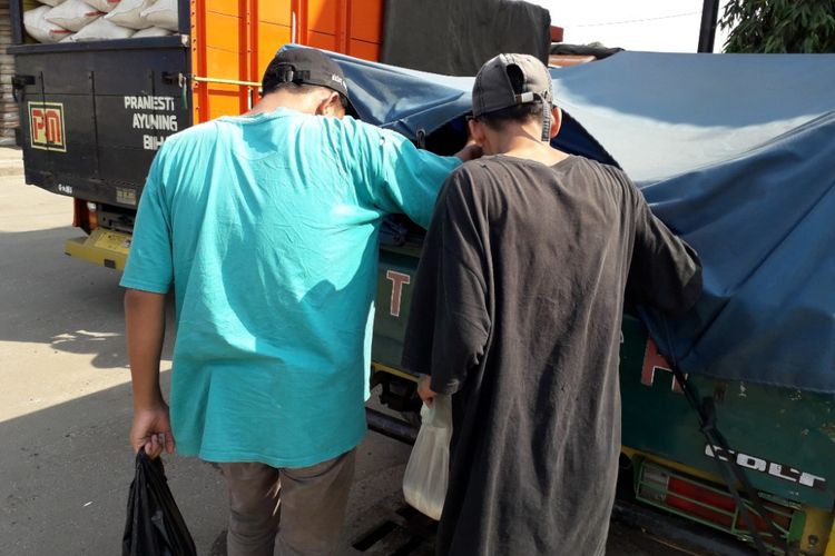 Diki dan Kamil sedang berburu beras ceceran dari sebuah mobil bak di Pasar Induk Cipinang, Jakarta Timur, Sabtu (12/5/2018).