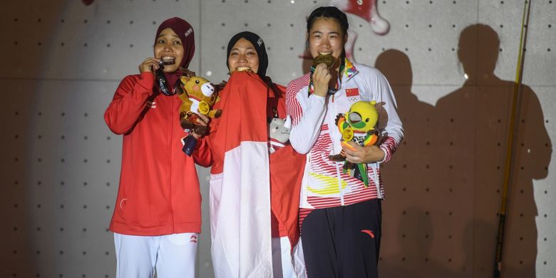 Atlet panjat tebing Indonesia peraih medali emas Aries Susanti Rahayu (tengah), Puji Lestari (kiri) dan atlet panjat tebing Cina He Cuilian (kanan) mengikuti penganugerahan medali seusai final katagori speed putri di Arena Panjat Tebing Jakabaring Sport City, Palembang, Sumatera Selatan, Kamis (23/8). ANTARA FOTO/INASGOC/Hendra Nurdiyansyah/nym/18.