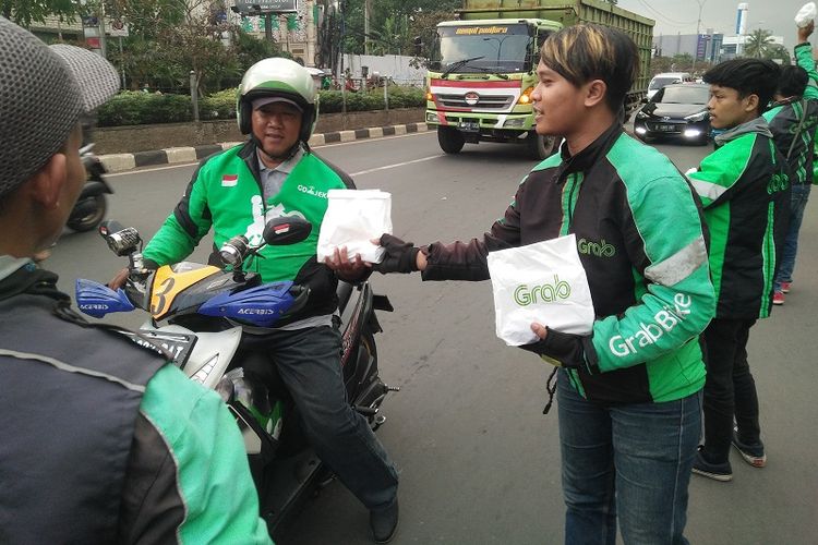 Sejumlah pengemudi ojek online membagikan takjil gratis kepada masyarakat umum dan pengendara di kawasan ITC Depok serta Stasiun Depok Baru, Senin (21/5/2018).