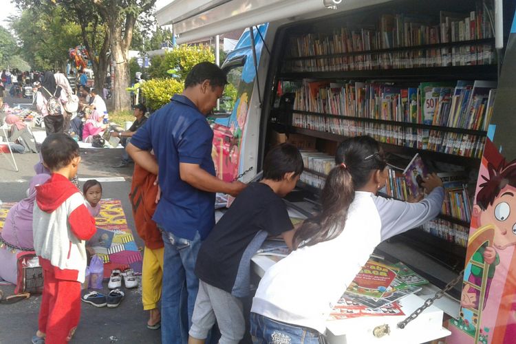 Nabila (11) dan pengunjung lain sedang memilih buku bacaan yang disediakan di mobil perpustakaan keliling di car free day (CFD) Solo, Jawa Tengah, Minggu (15/4/2018).