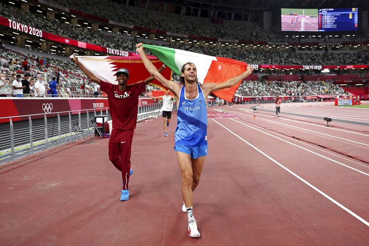 Peraih medali emas Mutaz Barshim, kiri, dari Qatar, dan Gianmarco Tamberi, dari Italia, merayakan kemenangan setelah berbagi emas setelah final lompat tinggi putra di Olimpiade Musim Panas 2020, Minggu, 1 Agustus 2021, di Tokyo, Jepang. 