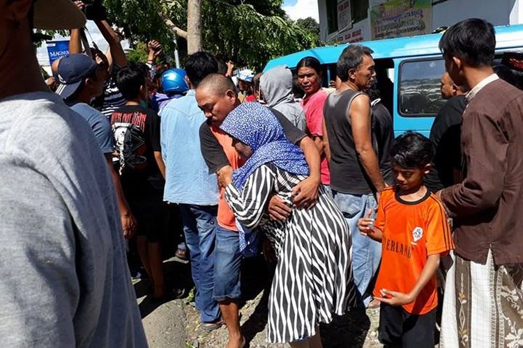 Seorang penumpang dievakuasi dari mikrolet yang mengalami kecelakaan, seorang lainnya masih terjepit di bagian depan kendaraan.