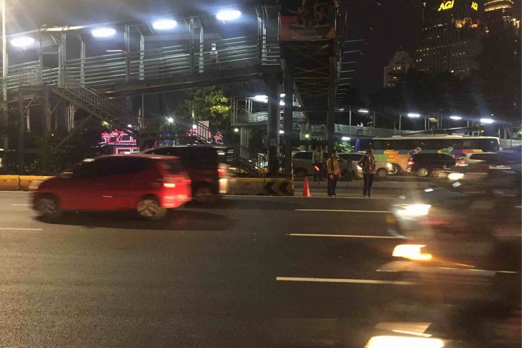 Sejumlah warga  bertaruh nyawa saat berusaha menyeberang jalan usai turun dari Jembatan Penyeberangan Orang (JPO)  Polda di Jalan Jenderal Sudirman, Jakarta Pusat, Senin (13/8/2018) malam. Pasalnya, tak ada pengamanan terhadap warga yang ingin menyeberang jalan menuju Jalan Jenderal Sudirman setelah turun dari JPO tersebut.