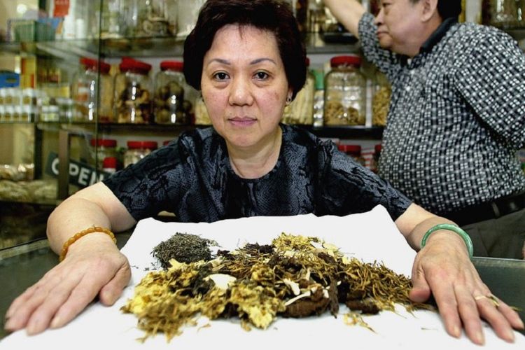 Jean Lam (C) and her husband Lam Hawk Yun (R), from the Win Duc Chinese Herbal Company in Sydneys Chinatown, displays 14 April 2003, her herbal tea remedy for the Severe Acute Respiratory Syndrome (SARS).  Although there have been only five suspected or possible cases of SARS Australia and none confirmed, the 132 deaths worldwide have prompted a rush on the herbal tea, the ingredients of which are fully imported from China.  AFP PHOTO/Greg WOOD / AFP PHOTO / GREG WOOD