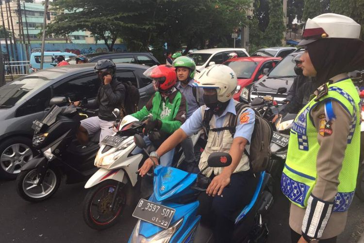 Petugas kepolisian mengedukasi cara menggunakan helm yang benar pada kampanye Gerakan Tertib Berlalu Lintas (GATEL) Otomania di pertigaan Kalibata