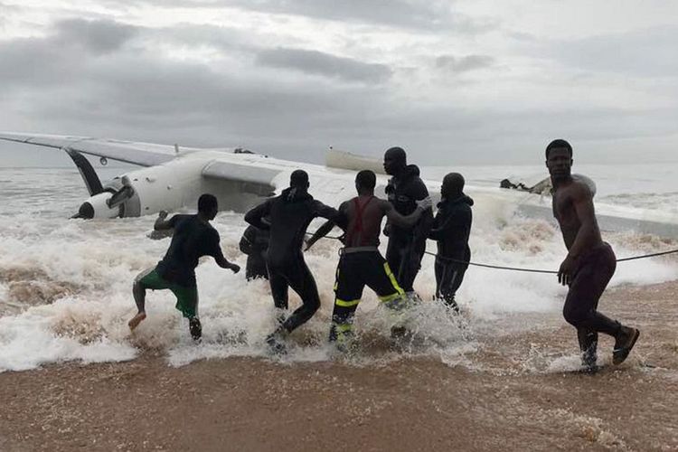 Penduduk membantu petugas untuk menarik bangkai pesawat kargo yang jatuh di dekat Bandara Internasional Abidjan, kota utama di Pantai Gading.