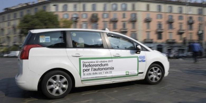 Sebuah taksi meluncur di jalanan kota Milan, Italia dengan ajakan menggelar referendum ditempelkan di badan mobil itu.