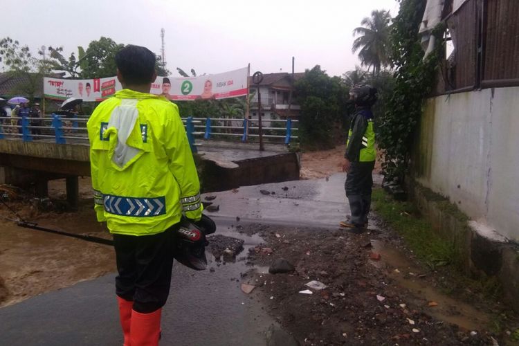 Petugas menjaga lokasi jembatan putus akibat banjir bandang di Desa Kalierang, Kecamatan Bumiayu, Brebes, Jawa Tengah, Rabu (25/4/2018).