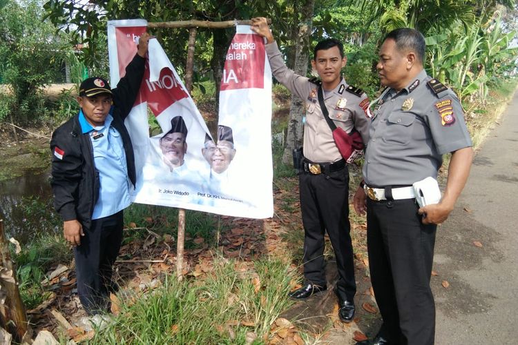 Sejumlah petugas Satgas Gakum berfoto di baliho Calon Presiden nomor urut 01, Joko Widodo, yang dirusak Rozi, Rabu (17/3/2019).