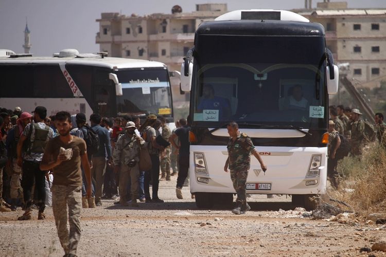 Anggota pasukan pemberontak menaiki bus yang akan membawa mereka meninggalkan wilayah Daraa setelah tercapai kesepakatan dengan pemerintah rezim Suriah.