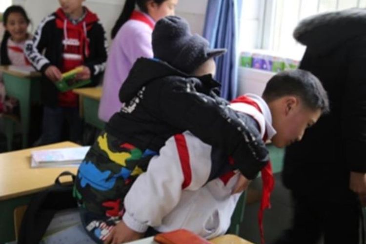 Xu Bingyang (12) menggendong Zhang Ze ke sekolah selama enam tahun terakhir. (Corriere)