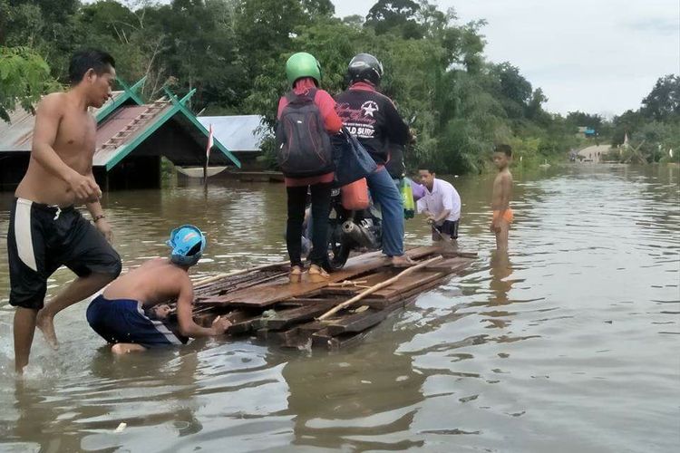 Warga terpaksa menyeberangkan sepeda motor dengan rakit di daerah Karang Taba-Sungai Tuat, akibat banjir yang membuat Jalan Trans Kalimantan putus di wilayah Kabupaten Lamandau