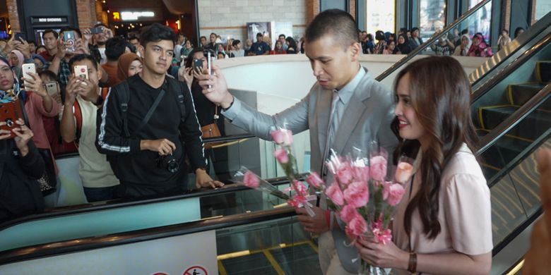 Artis peran Shandy Aulia dan Samuel Rizal saat membagikan bunga pada penggemar di pemutaran khusus film Eiffel Im In Love 2 di CGV Grand Indonesia, Tanah Abang, Jakarta Pusat, Minggu (11/2/2018).
