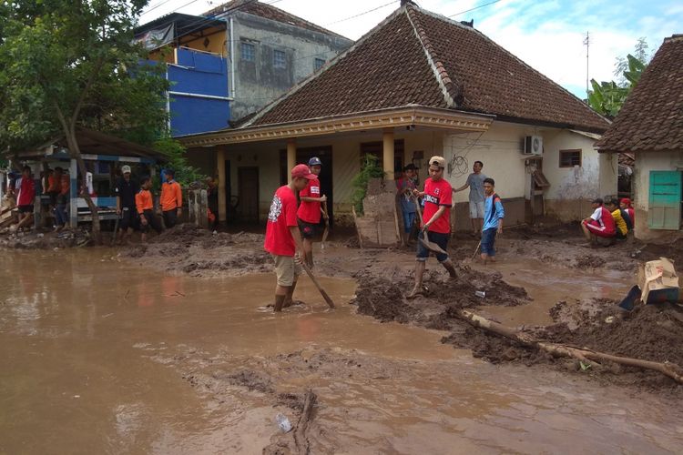 Para relawan sedang membersihkan lumpur yang merendam rumah di Desa Alasmalang Banyuwangi