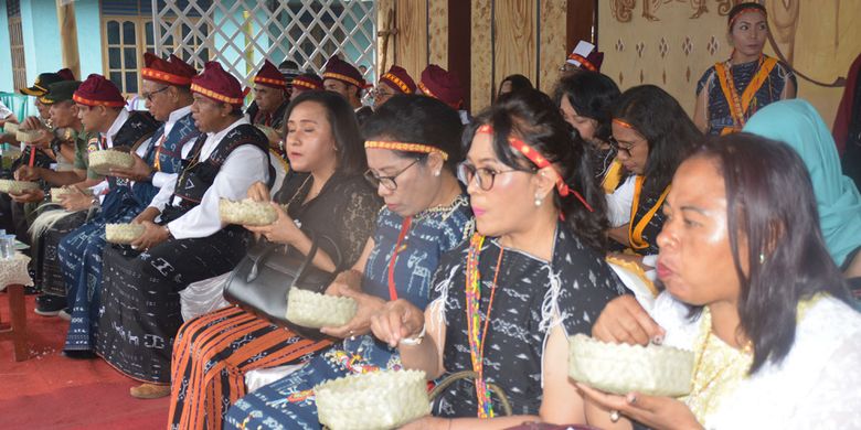 Para istri pejabat dari lingkungan Pemprov NTT dan Kabupaten Ngada makan uwi (ubi) bercampur nasi dengan wadah wati pengganti piring pabrik saat Ritual Reba Ngada dilangsungkan di Kampung Langa, Kecamatan Bajawa, Kabupaten Ngada, Flores, NTT, Selasa (15/1/2019).