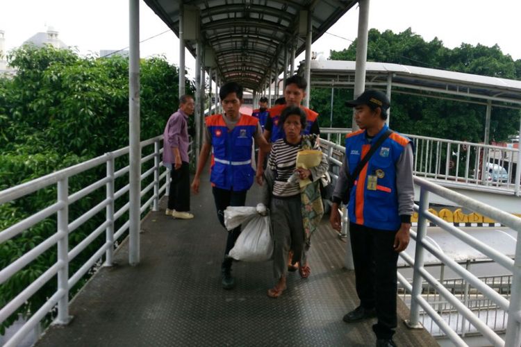 Petugas Suku Dinas Sosial Jakarta Pusat menjangkau pengemis bernama Sri di jembatan penyeberangan orang (JPO) Kramat Sentiong, Senin (13/11/2017).