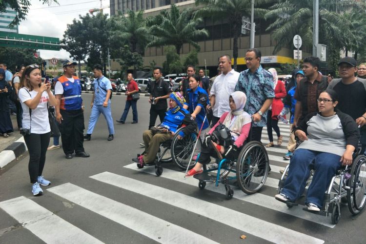 Gubernur DKI Jakarta Anies Baswedan mendorong pengguna kursi roda melintasi Jalan M.H Thamrin, Sabtu (10/3/2018). 