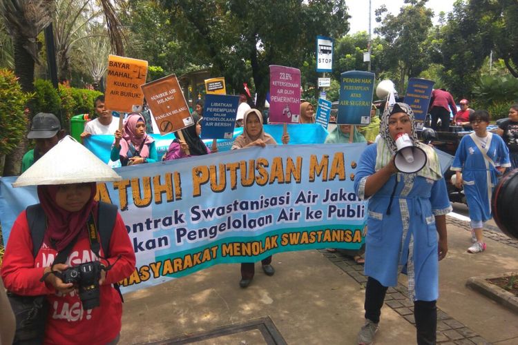 Massa yang didominasi ibu-ibu melakukan aksi mandi bareng di depan kantor Balai Kota DKI Jakarta, Rabu (22/3/2018).