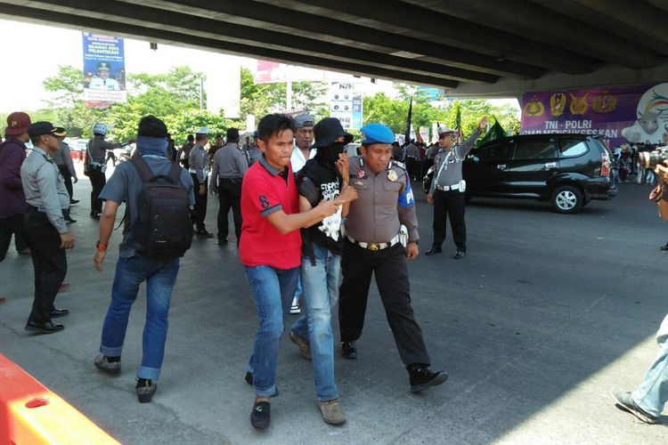 Salah seorang mahasiswa yang terlibat kericuhan dengan aparat kepolisian diamankan saat berdemonstrasi di flyover Makassar,  Rabu (2/5/2018) siang. 