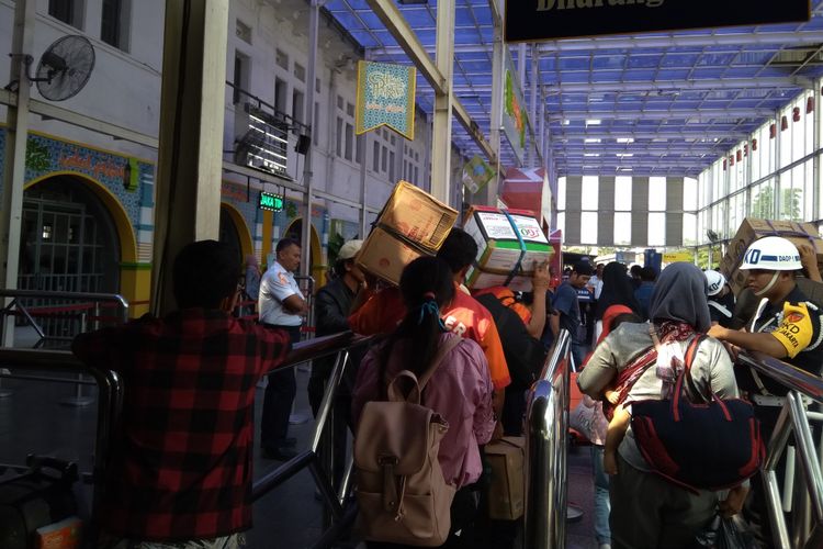 Porter atau pramuantar sedang membawa barang bawaan penumpang di Stasiun Pasar Senen, Rabu (13/6/2018).