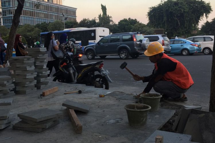 Sejumlah pekerja melakukan memasang material untuk pekerjaan revitalisasi trotoar di depan Patung Pemuda Membangun, Senayan, Jakarta Selatan, Jumat (6/7/2018). Revitalisasi ini dilakukan dalam rangka menyambut Asian Games 2018.