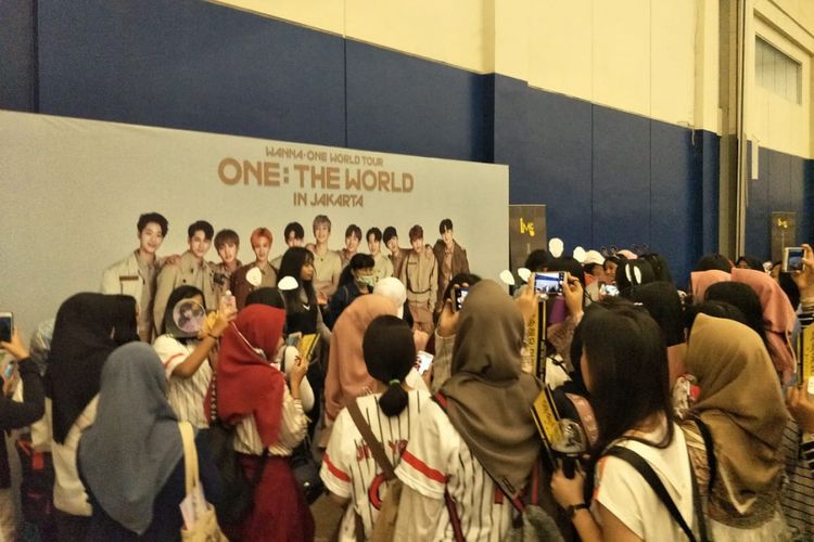 Para wannables berfoto di depan poster besar Wanna One sebelum memasuki gedung tempat boyband K-pop tersebut menggelar konser One: The World di Indonesia Convention Exhibition, BSD City, Tangerang, Minggu (15/7/2018).