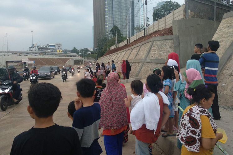 Warga menunggu mobil Presiden Joko Widodo melintas dari peresmian Tol Depok-Antasari, Kamis (27/9/2018).