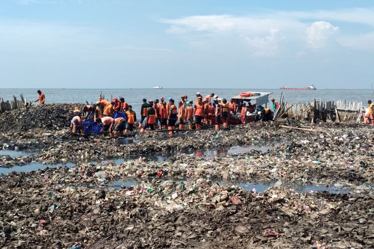 Petugas Dinas Lingkungan Hidup Kepulauan Seribu membersihkan sampah di Muara Angke, Minggu (18/3/2018)