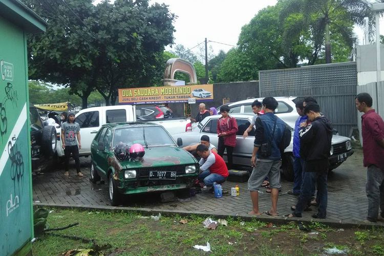 Sejumlah warga sedang memperbaiki mobil Charade yang rusak