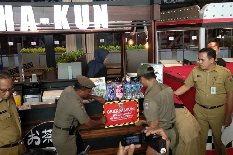 Pemasangan stiker penunggak pajak di salah satu mal di Cakung, Jakarta Timur, Selasa (24/4/2018)