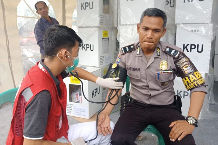 Seorang relawan kesehatan PMI Kota Pontianak, Kalimantan Barat, memeriksa kesehatan petugas kepolisian yang berjaga di Kantor Camat Pontianak Barat, Senin (22/4/2019).