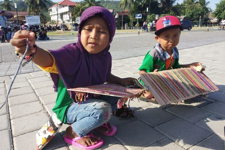 Dua bocah yaitu Mika dan Ogi sedang menjajakan gelangnya kepada wisatawan di pantai Kuta Lombok Tengah, Kamis (6/6/2019)