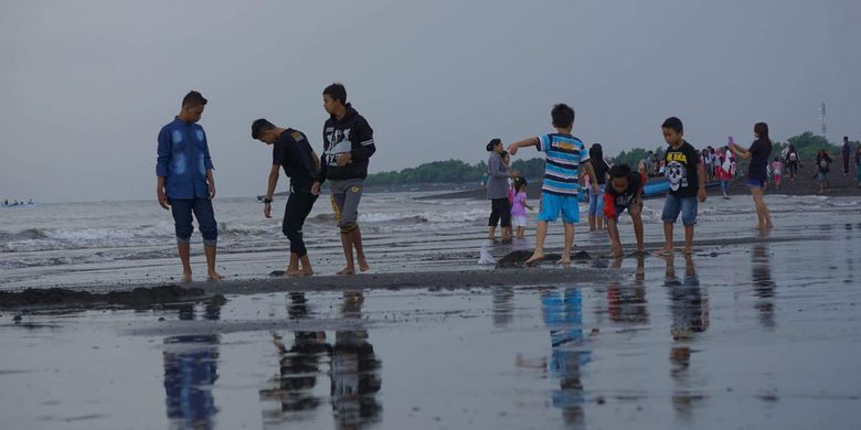 Wisatawan sedang bermain air di Pantai Boom Banyuwangi, Jawa Timur yang berhadapan langsung dengan Selat Bali.