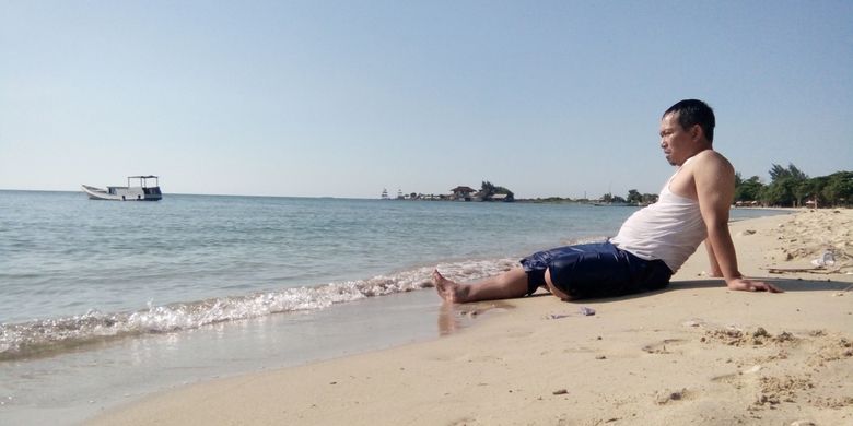 Seorang pengunjung tengah berjemur, sembari menunggu keluarganya bermain air di Pantai Bondo,  Jepara,  Jawa Tengah, Sabtu (5/5/2018). 