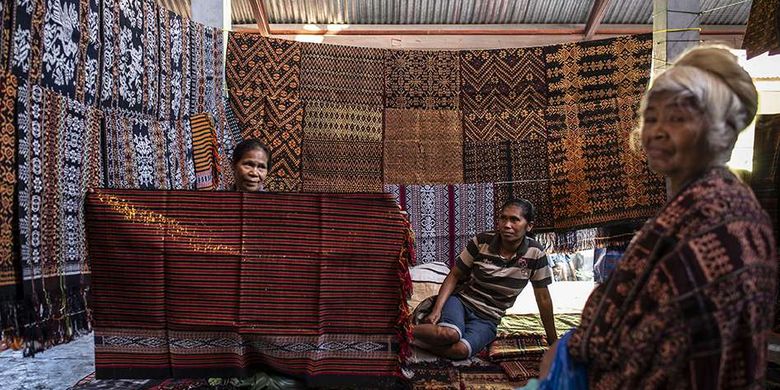 Pengrajin menunjukkan motif kain tenun ikat kepada calon pembeli di Pasar Alok, Maumere, Sikka, Nusa Tenggara Timur (NTT), Selasa (31/7/2018). Di Pasar Alok, setiap Selasa mulai pukul 06.0013.00 Wita merupakan hari khusus bagi perajin seantero Kabupaten Sikka dan daerah lainnya untuk menjual kain tenun ikat hasil kerajinan tangan yang dibuat dengan mesin tenun tradisonal.