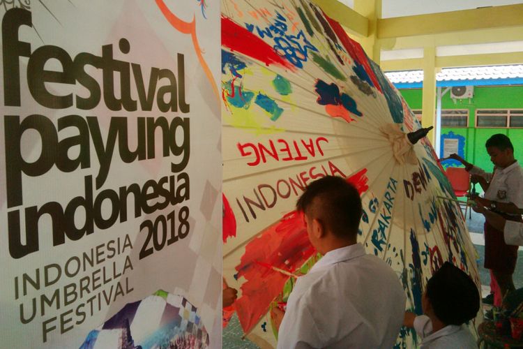 Siswa penyandang disabilitas YPAC Solo, Jawa Tengah melukis payung raksasa pre-event Festival Payung Indonesia ke-5 Tahun 2018, Selasa (21/8/2018).