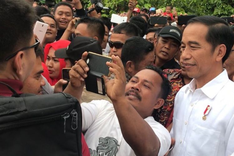 Presiden Joko Widodo saat diminta swafoto bersama salah satu warga di Kabupaten Dharmasraya, Sumatera Barat. 