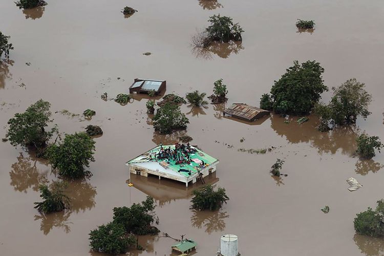 Orang-orang mengungsi dan tertahan di atap bangunan yang dikelilingi oleh banjir, di daerah yang terdampak topan Idai di Beira, Mozambik, Senin (18/3/2019). Ratusan orang tewas dan lainnya hilang di Mozambik dan Zimbabwe setelah topan Idai membawa serta banjir bandang dan angin kencang, 17 Maret lalu.