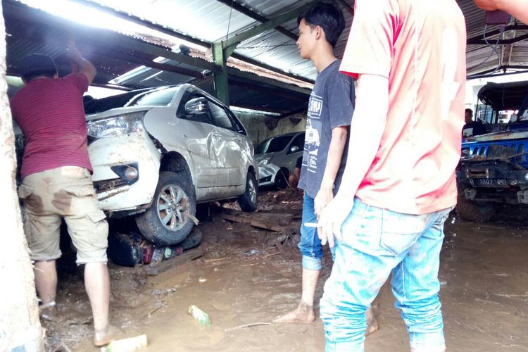 Para pekerja gudang furnitur dan warga tengah mengevakuasi belasan mobil yang tertumpuk akibat terbawa arus banjir bandang di gudang furnitur, Jalan AH Nasution, Kelurahan Cicaheum, Kecamatan Kiaracondong, Kota Bandung, Rabu (21/3/2018).