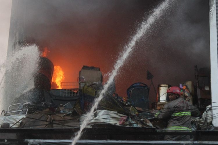 Seorang petugas damkar berupaya menjangkau titik api dalam peristiwa kebakaran di sebuah ruko di kawasan Pasar Baru, Cianjur, Jawa Barat, Selasa (25/06/2019) pagi