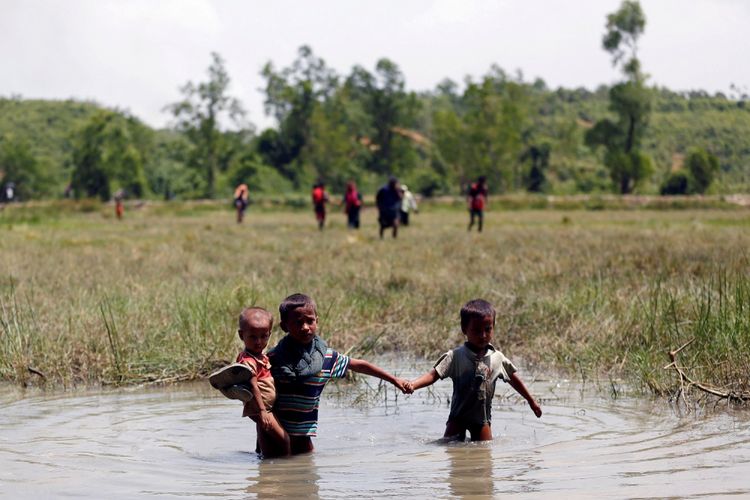 Anak-anak Rohingya berjalan melewati air saat mereka berusaha untuk masuk ke Bangladesh dari No Mans Land setelah sebuah tembakan terdengar dari sisi Myanmar, di Coxs Bazar, Bangladesh, Senin (28/8). 